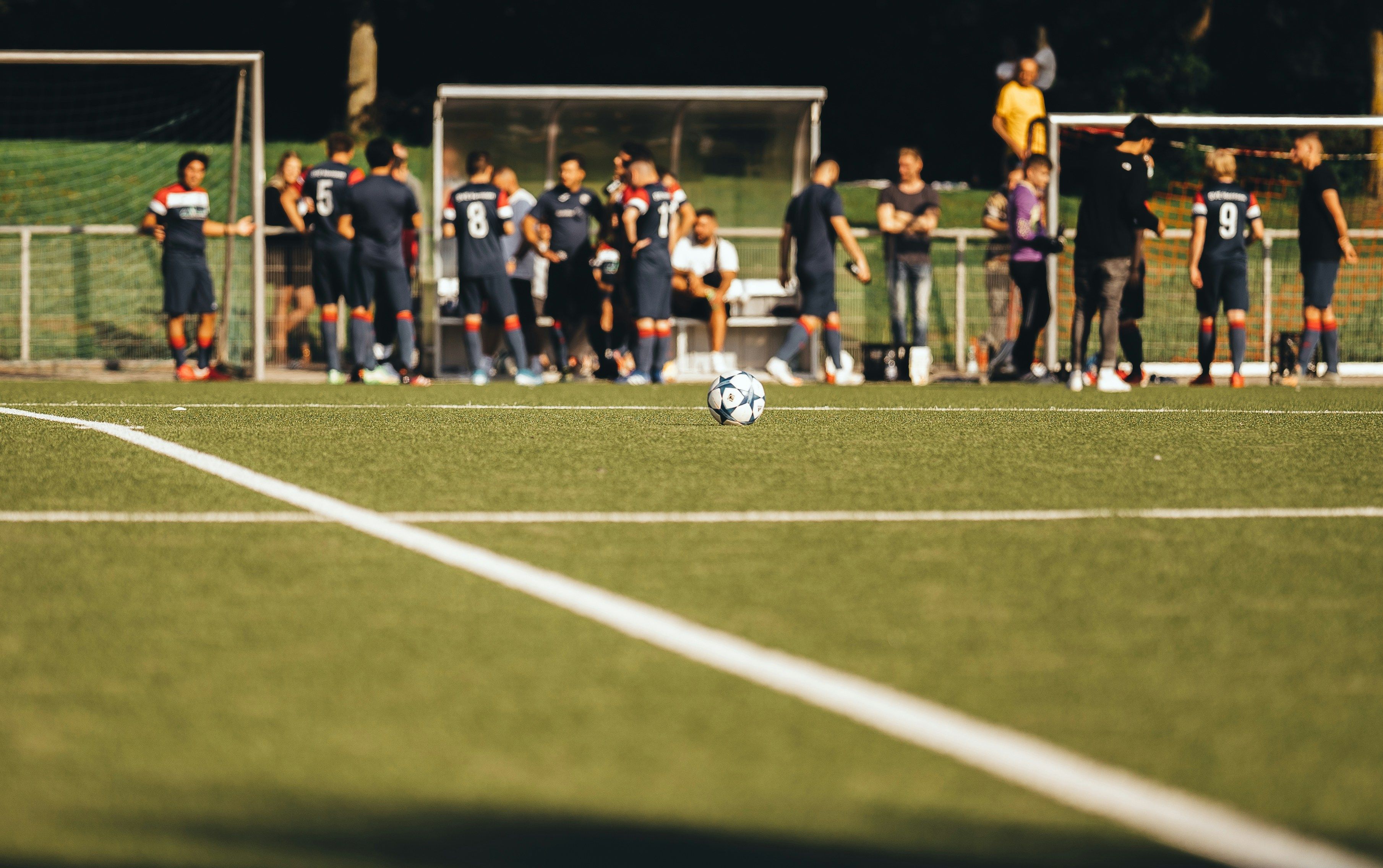 Community soccer — players on the sideline and a ball on the field during a Saturday morning game